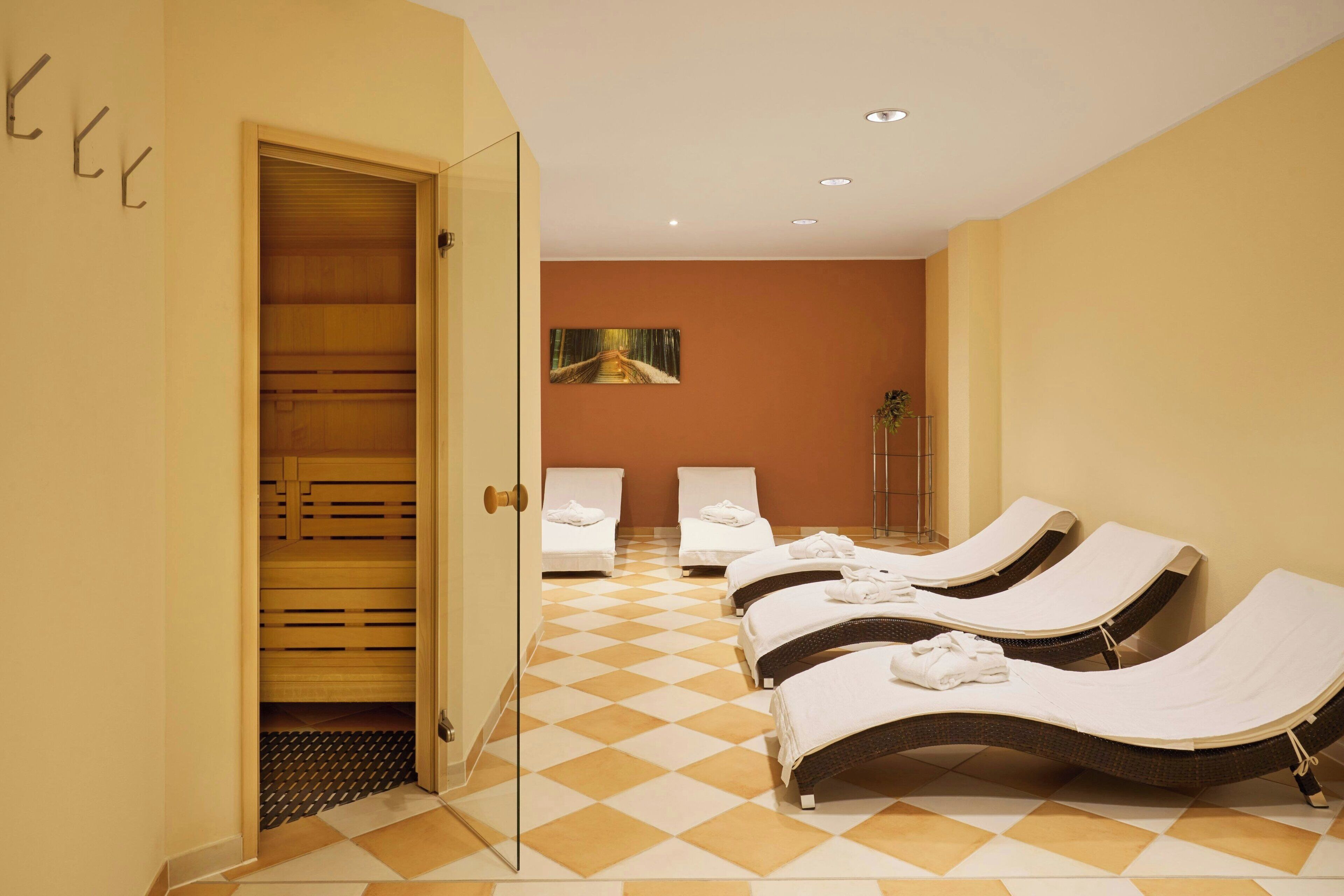 A hotel room with a checkered floor, a wooden door, and a bed with a white cover.