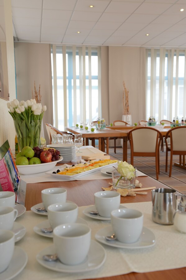 A dining area with tables set for breakfast, including fruits, pastries, and white cups. - Hotel Residenz Oberhausen (Oberhausen)