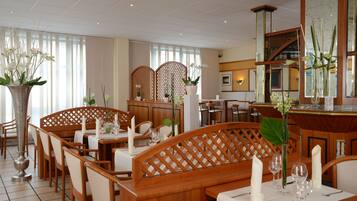 Ein Restaurant mit Holztischen, weißen Tischdecken und floralen Dekorationen.