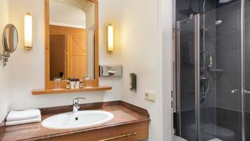 A bathroom with a sink, mirror, and shower.