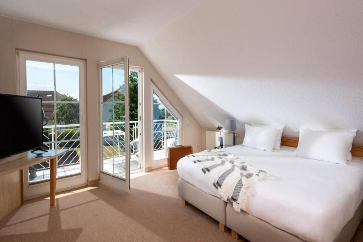 Une chambre à coucher avec un lit, une télévision et un balcon offrant une vue.