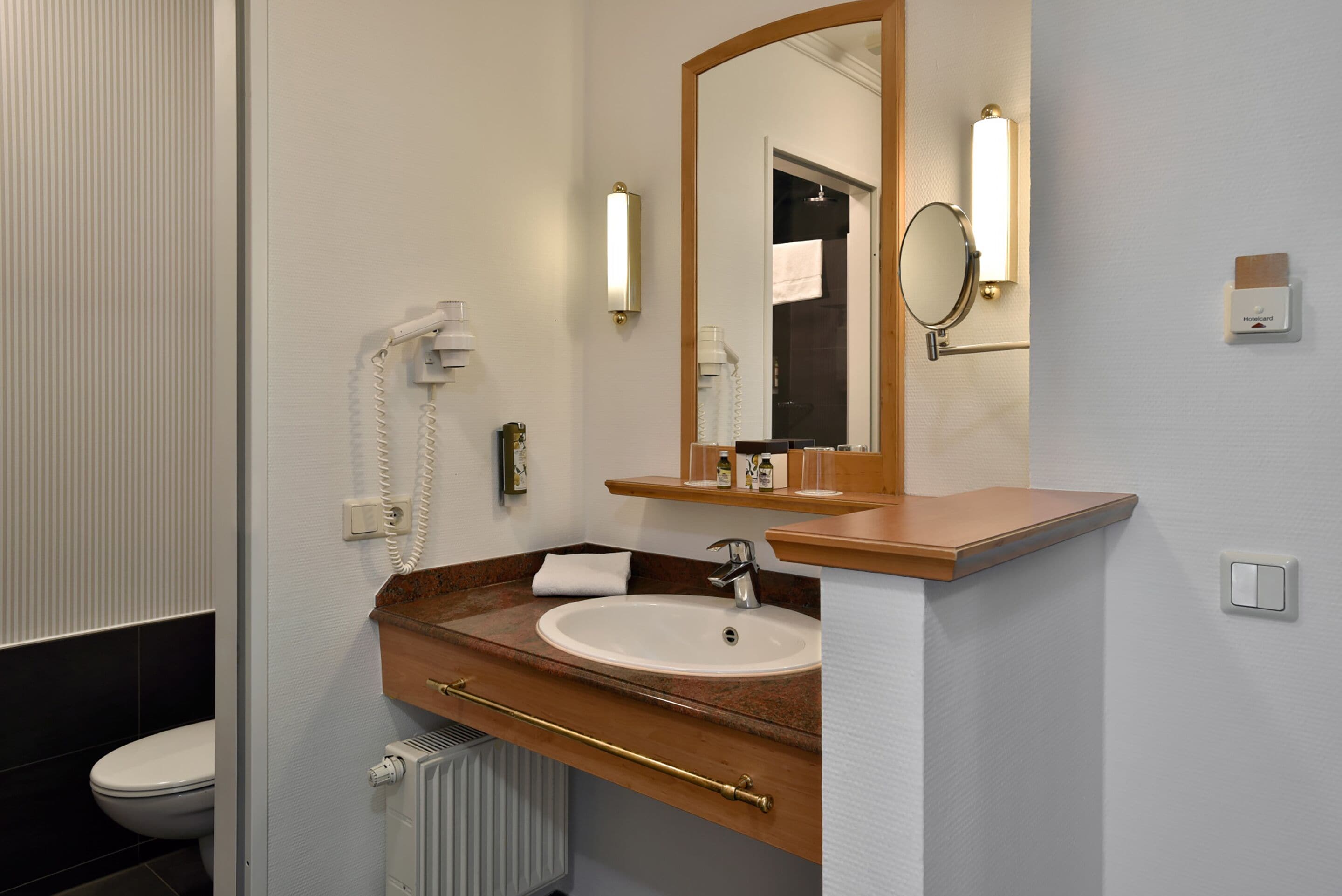 A bathroom with a white sink, a mirror, a towel, and a telephone.