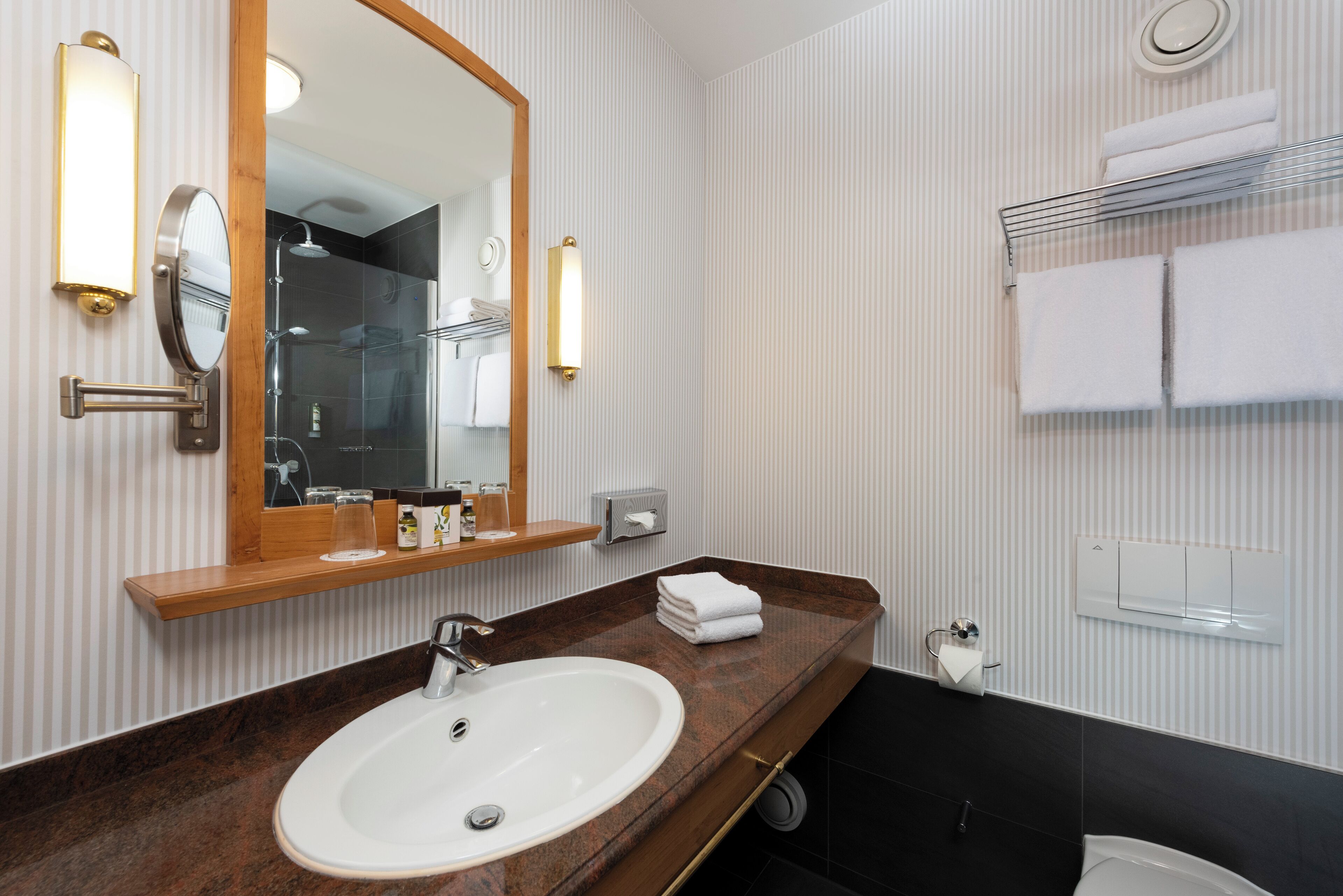 Een badkamer met een marmeren wastafel, een grote spiegel en een handdoekrek.
