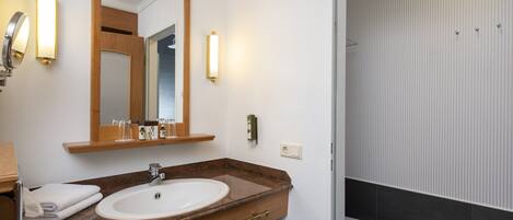 Une salle de bain avec un meuble-lavabo en bois, un lavabo blanc, un miroir et des toilettes.