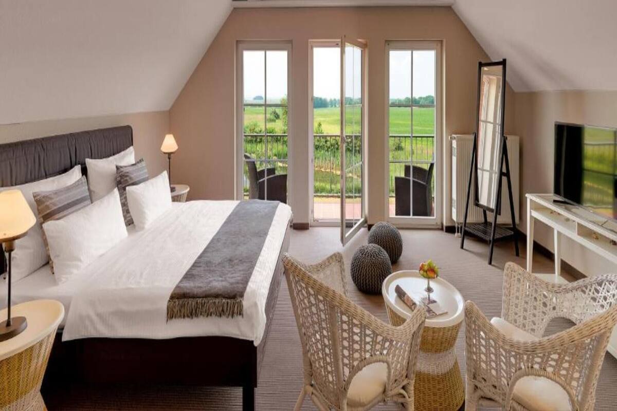Une chambre à coucher avec un lit, une table de chevet, une lampe et une vue sur l’extérieur.