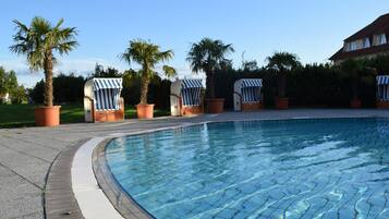 A swimming pool with lounge chairs and palm trees.