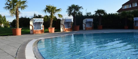 A swimming pool with lounge chairs and palm trees.