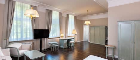 Una habitación de hotel con cama, escritorio, silla, televisión y armario.