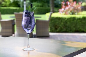 A clear glass with ice and a mint garnish on a table outdoors.