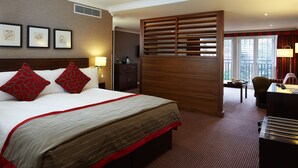 Habitación de hotel con una cama grande, un escritorio y vistas al exterior por la ventana.