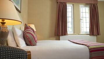 A neatly arranged hotel room with a bed, two bedside lamps, a window with curtains, and a radiator.
