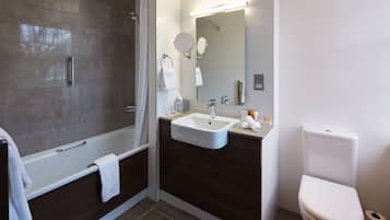 Ein modernes Badezimmer mit einer Badewanne, einem Waschbecken, einer Toilette und einem großen Spiegel.