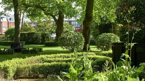 Un jardín bien cuidado con setos recortados y árboles maduros.