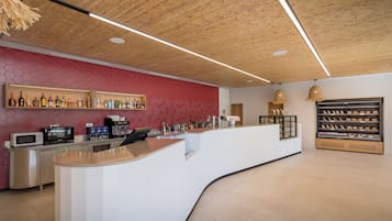 Zona de bar moderna con una barra curva, estantes llenos de bebidas y un muro con patrón hexagonal.