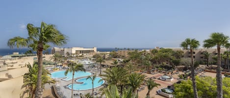Ein Resort mit großem Pool, Palmen und Blick aufs Meer.