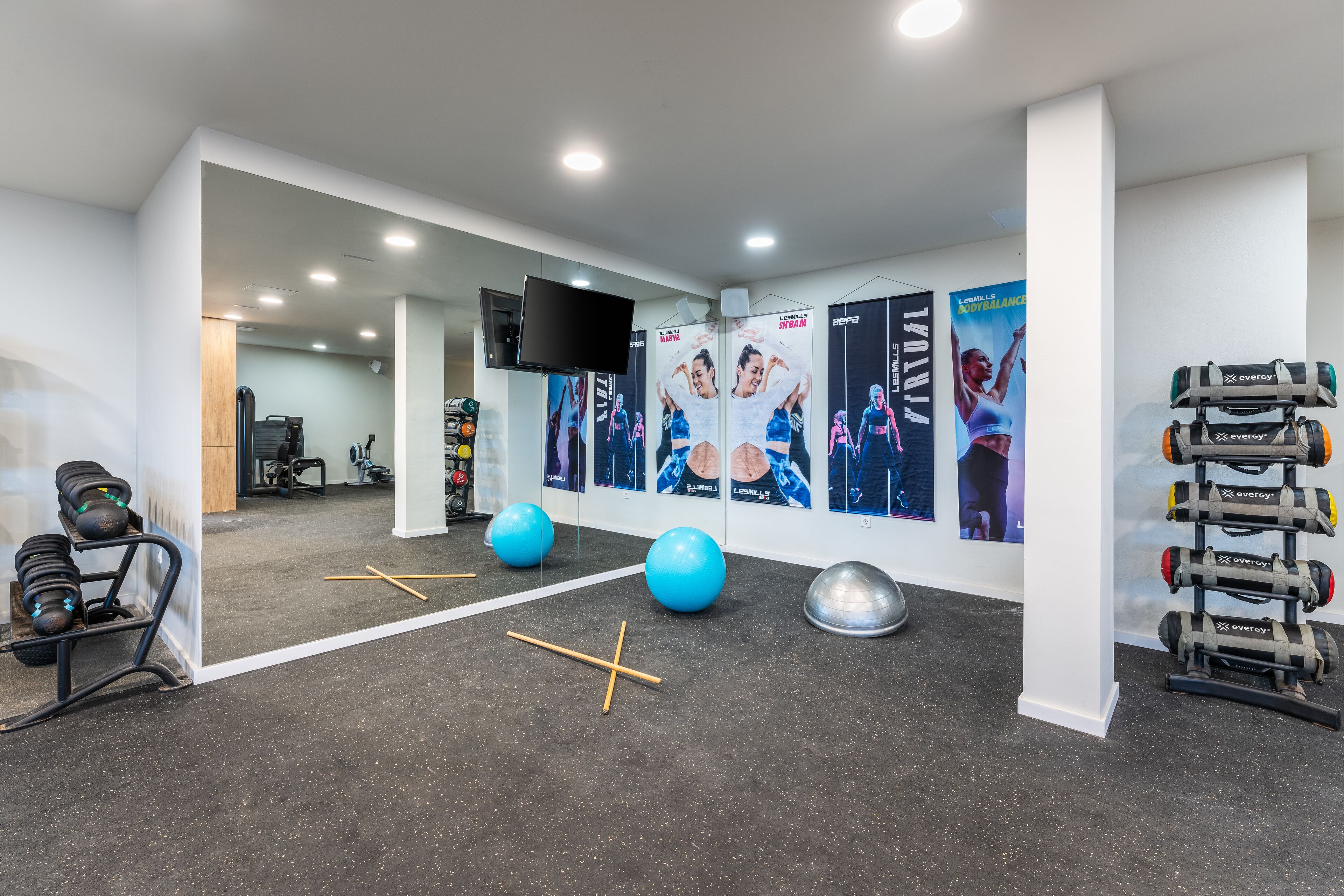 A modern gym with exercise equipment, posters, and a large mirror.