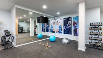 A modern gym with exercise equipment, posters, and a large mirror.