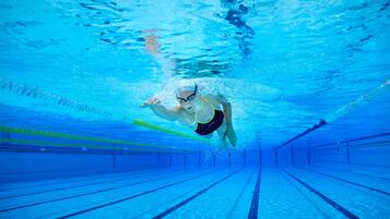 Vista subacuática de una persona nadando en una piscina con separadores de carril.