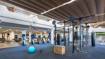 Un gimnasio con cintas de correr, elípticas, un saco de boxeo y una zona de dominadas.