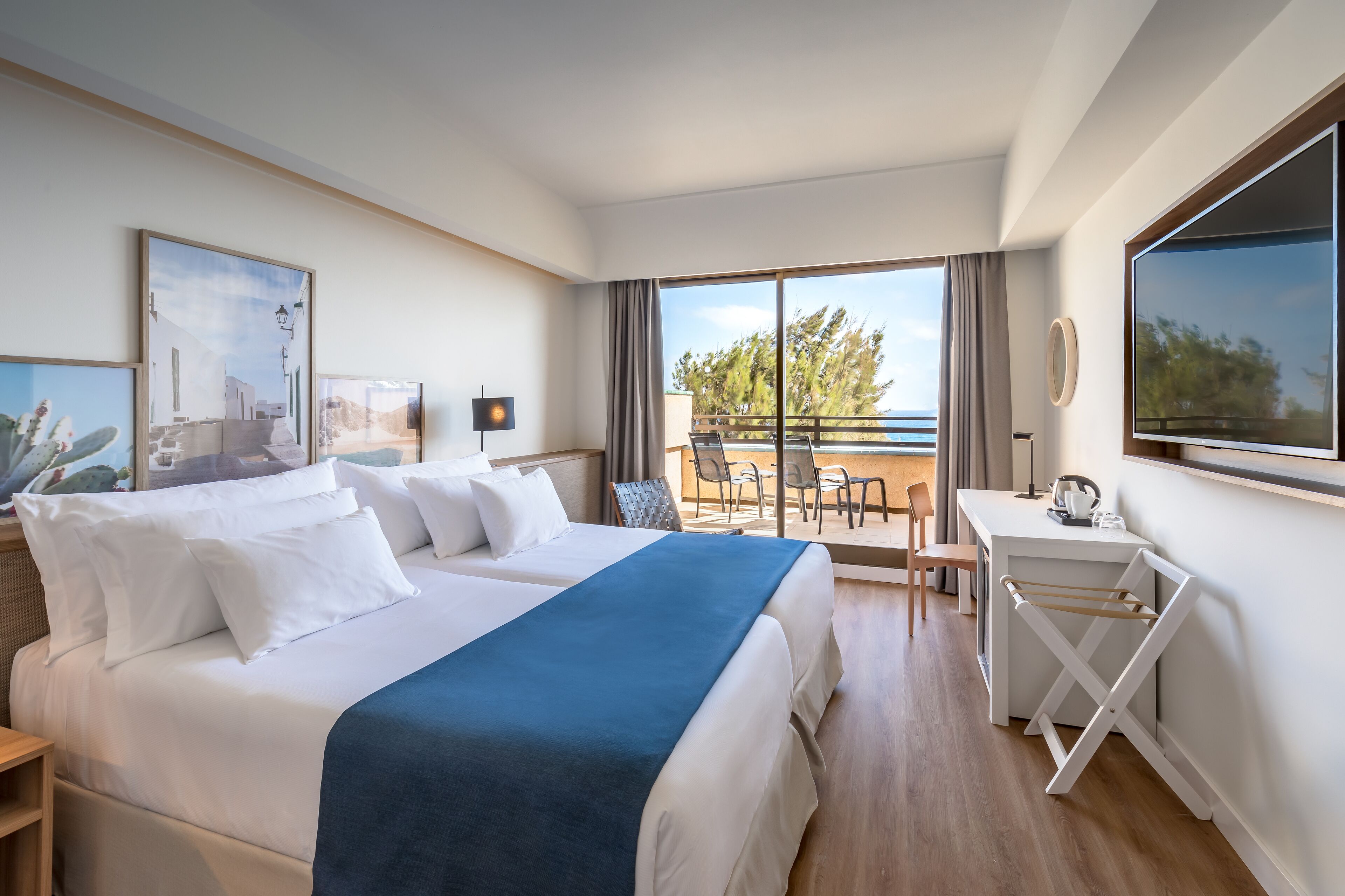 A hotel room with a large bed, a desk, and a balcony with a view.