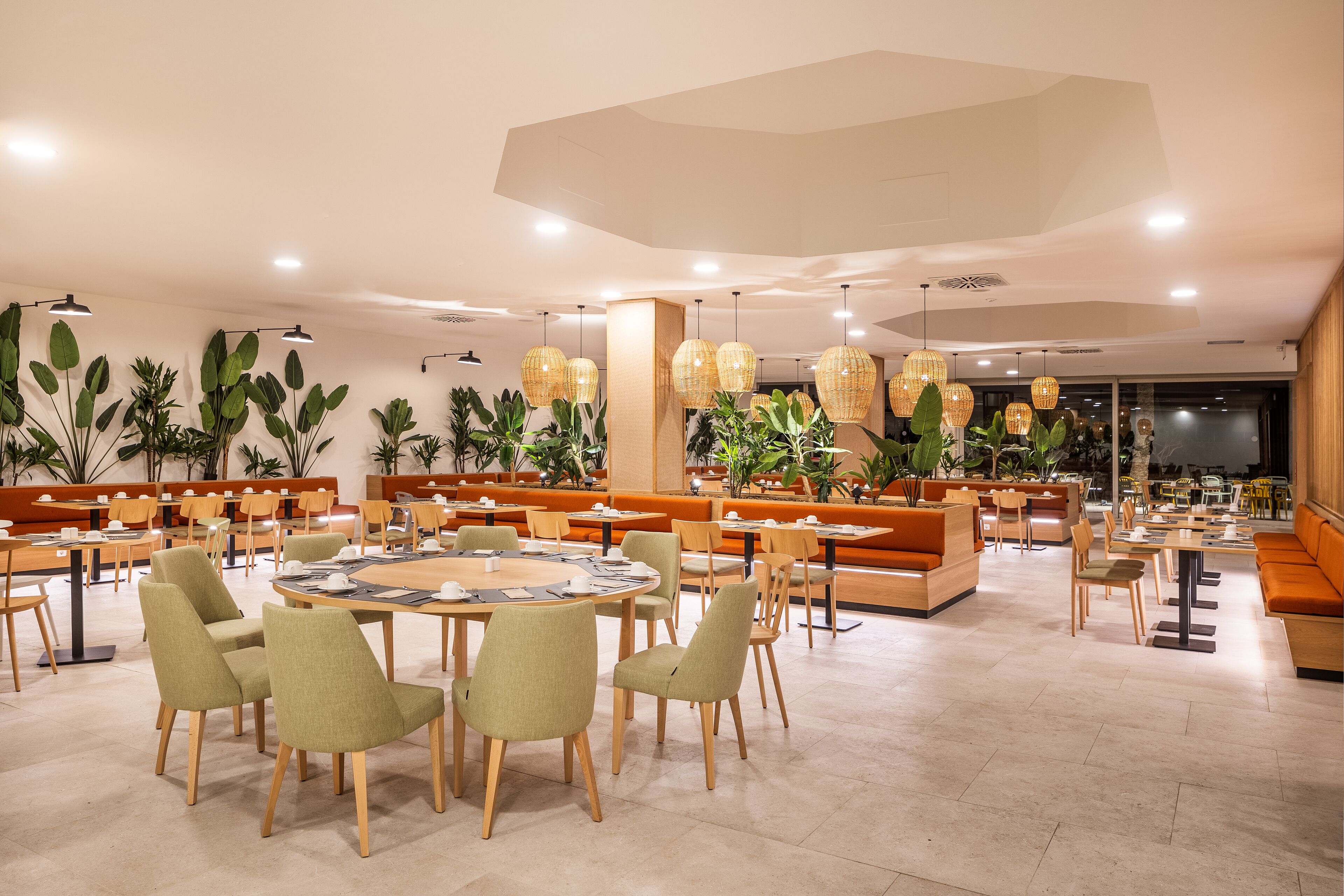 Un vaste espace dédié à la salle à manger, avec des tables rondes, des sièges confortables et des luminaires suspendus.