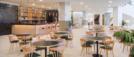 Eine moderne Bar mit gefliestem Rückspritzguss, Holzböden und verschiedenen Sitzgelegenheiten, darunter runde Tische und Stühle.