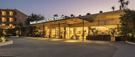 L’extérieur du Barceló Lanzarote Active Resort, avec son entrée couverte, ses palmiers et un ciel dégagé.