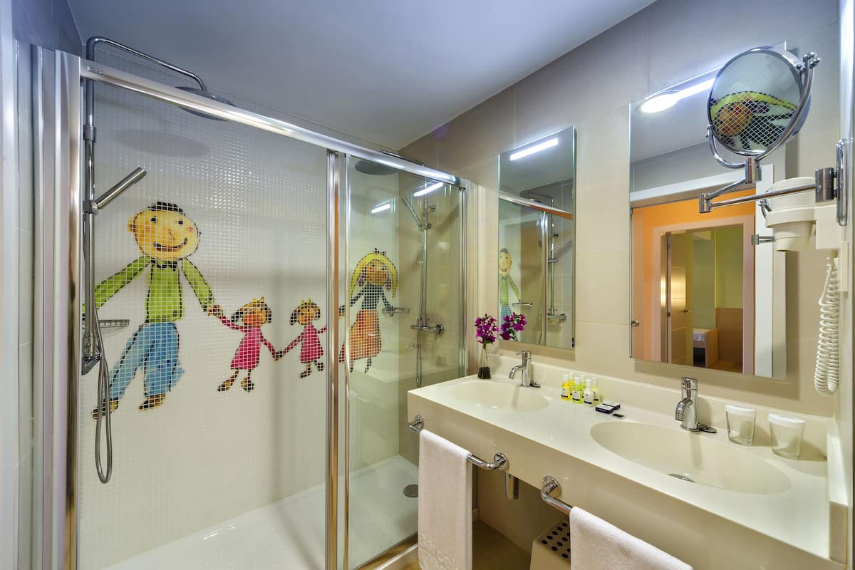 Un baño con cabina de ducha de vidrio, un lavabo con espejo y un perchero para toallas.
