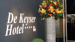 Letrero del Hotel De Keyser con un gran arreglo floral al frente.