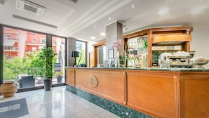 A hotel reception area with a marble counter, a coffee machine, and a view of a red building outside. - Hotel Federico II (L'Aquila)