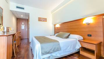 Une chambre d’hôtel avec un lit en bois, une table de chevet et un bureau avec des chaises.