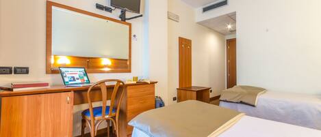 A hotel room with a desk, chair, bed, and a television mounted on the wall.