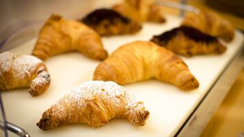 A variety of pastries, including croissants and pastries dusted with powdered sugar, displayed on a tray.