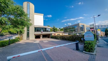 A hotel entrance with a modern design, a clear sky, and a paved pathway leading to the entrance.