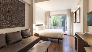 Ein Hotelzimmer mit Bett, einer Couch, einem Schreibtisch, einem Fernseher und einem Wandbild.