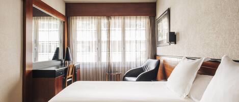 Una habitación de hotel con una cama grande, un escritorio, una silla y una mesita.