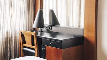 Habitación de hotel moderna con un escritorio de madera, una lámpara negra y un espejo.