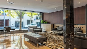 Eine moderne Lobby mit Ledersofas, einem gemusterten Teppich und einer großen Säule aus Marmor.