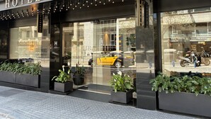 The exterior of Hotel Balmoral with large glass windows, a modern facade, and potted plants at the entrance.