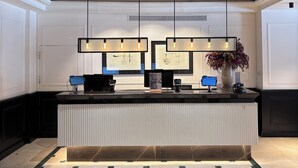 A reception desk with a modern design, featuring a black countertop, multiple computer monitors, and a vase with flowers.