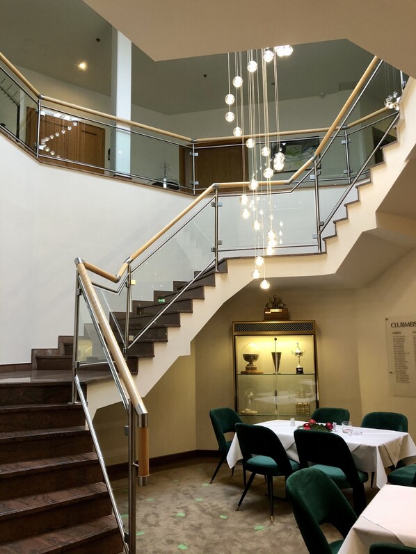 A multi-level interior with a staircase, dining area, and a trophy display.