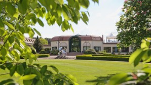 A building with a central arched entrance, surrounded by a well-manicured lawn and hedges. - GolfResort Semlin (Rathenow)