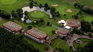 An aerial view of a golf course with a clubhouse, a pond, and surrounding greenery. - GolfResort Semlin (Rathenow)