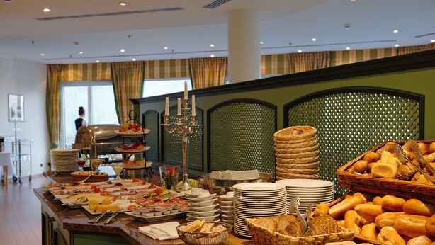 A buffet with various food items and utensils, including bread, fruits, and plates. - GolfResort Semlin (Rathenow)