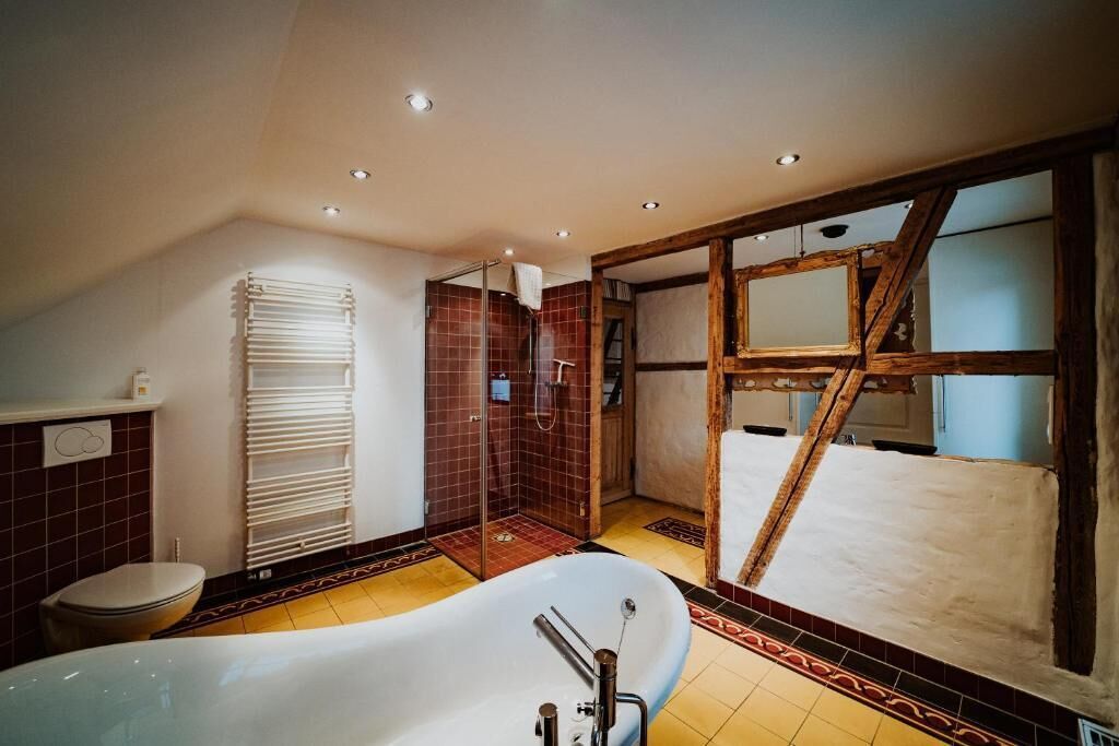 Un baño con bañera, ducha y zona de ducha con mampara de vidrio.