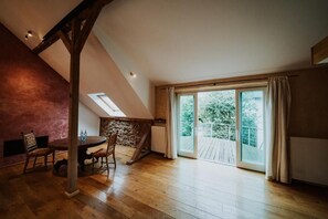 Une pièce spacieuse dotée d’un plancher en bois, d’une table à manger avec des chaises, d’un mur décoratif en pierre et d’une grande porte-fenêtre coulissante donnant sur une terrasse extérieure.