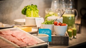 A buffet with various food items including ham, cheese, lettuce, and a green drink.