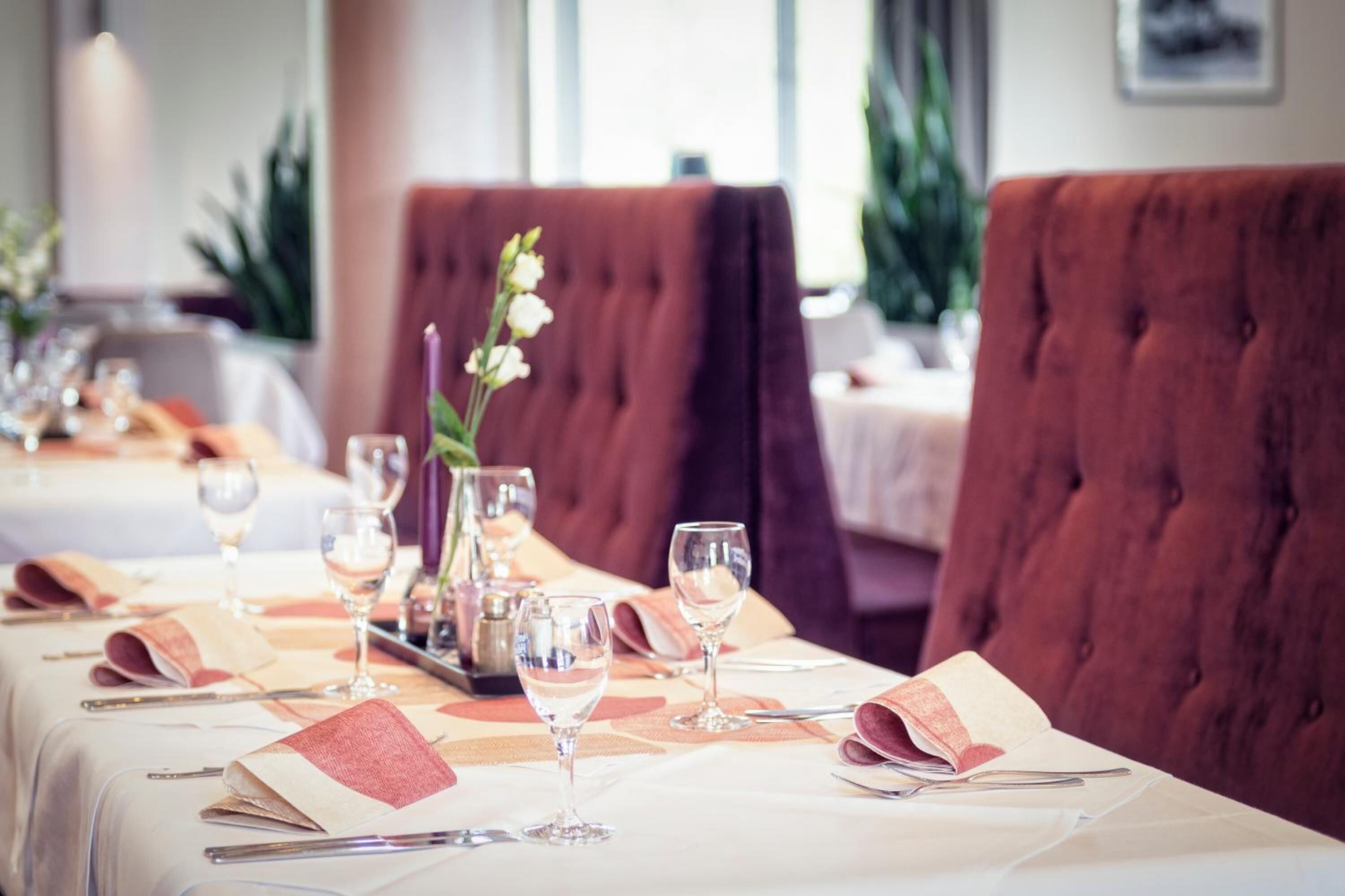 A dining table set with wine glasses, cutlery, and a centerpiece.