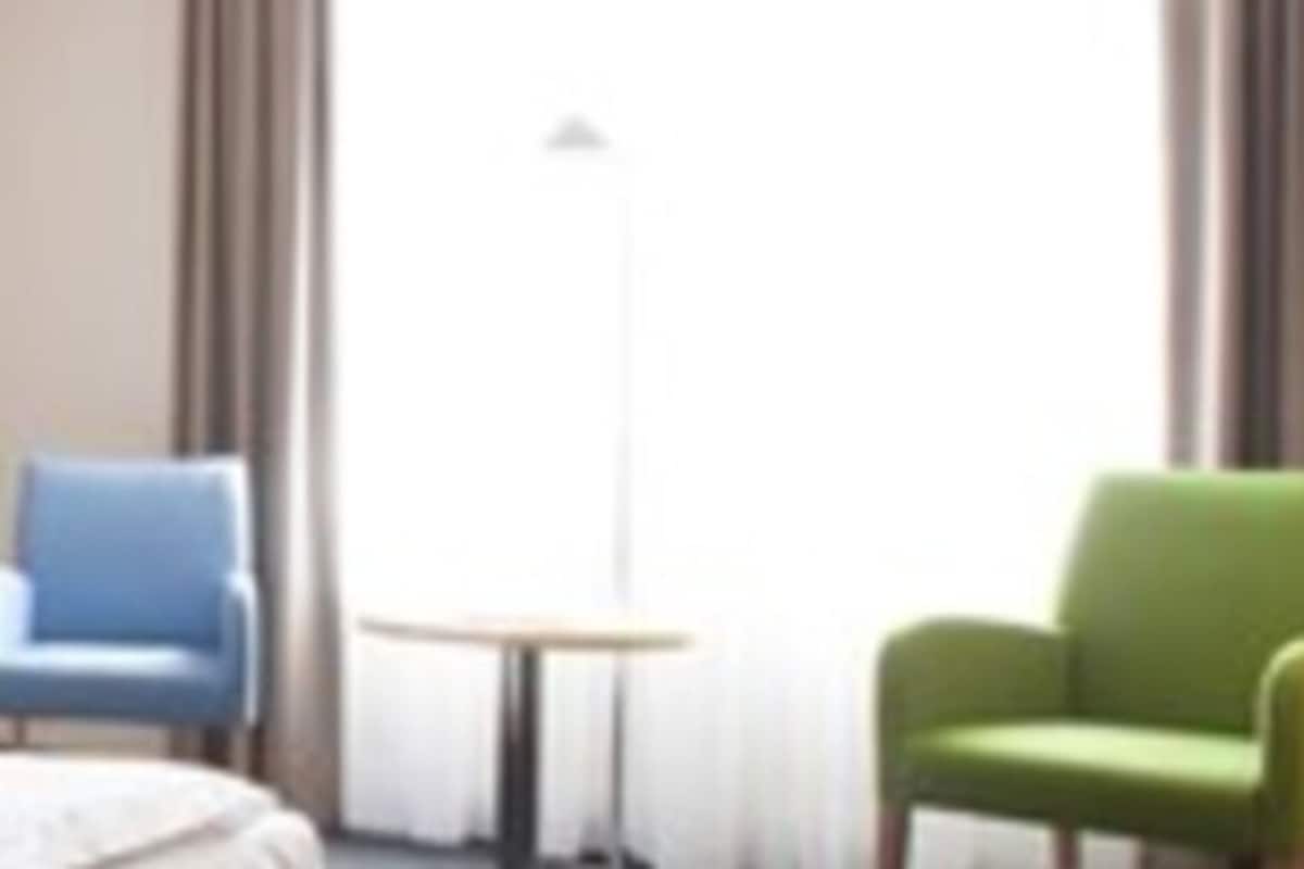 A hotel room with a bed, a chair, and a small table.
