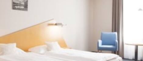 A hotel room with a bed, a chair, and a small table.